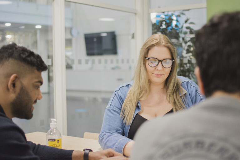 Opiskelijat istumassa pöydän ääressä.