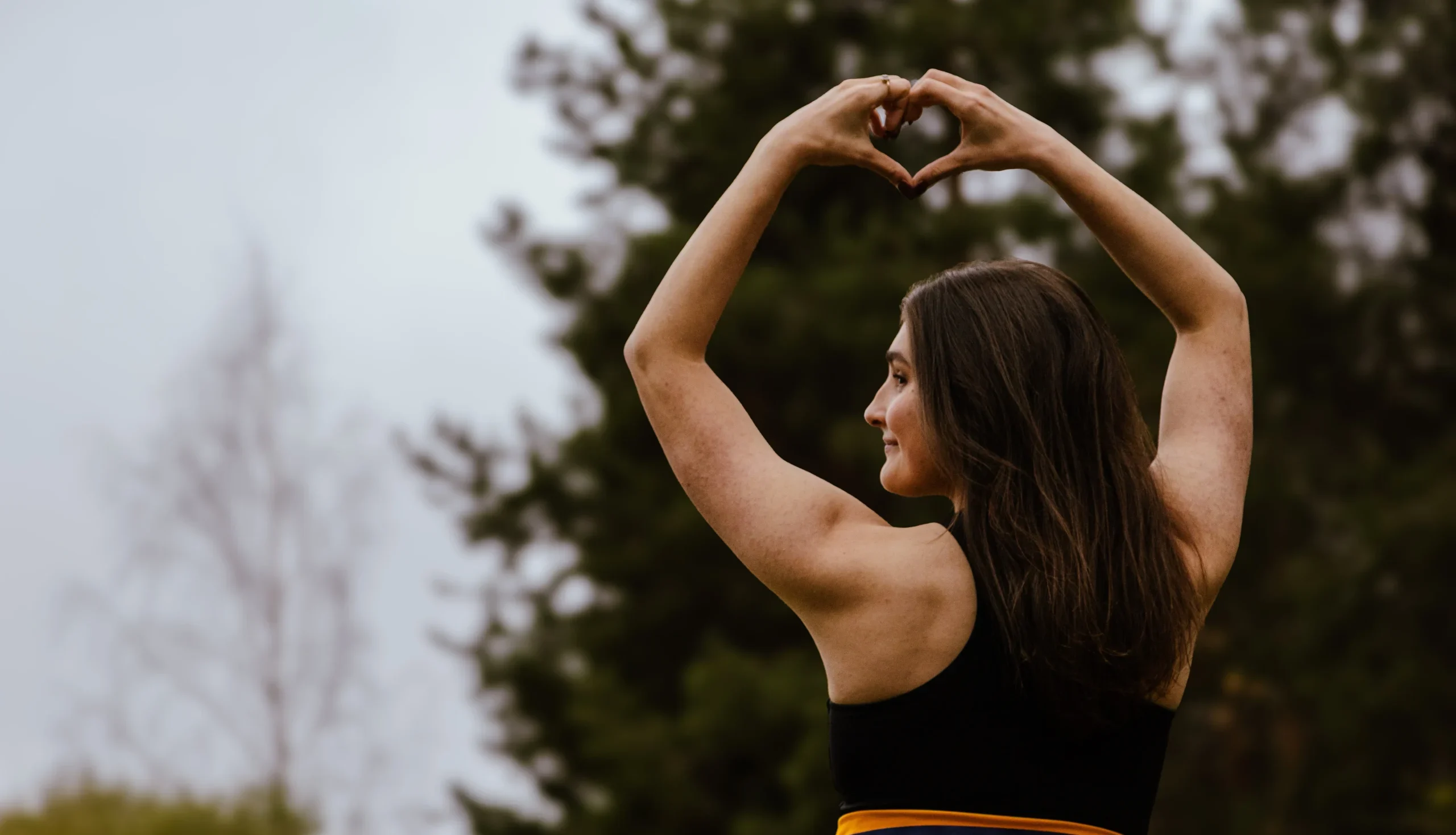 Opiskelija selkä kameraan näyttää sydän-merkkiä.